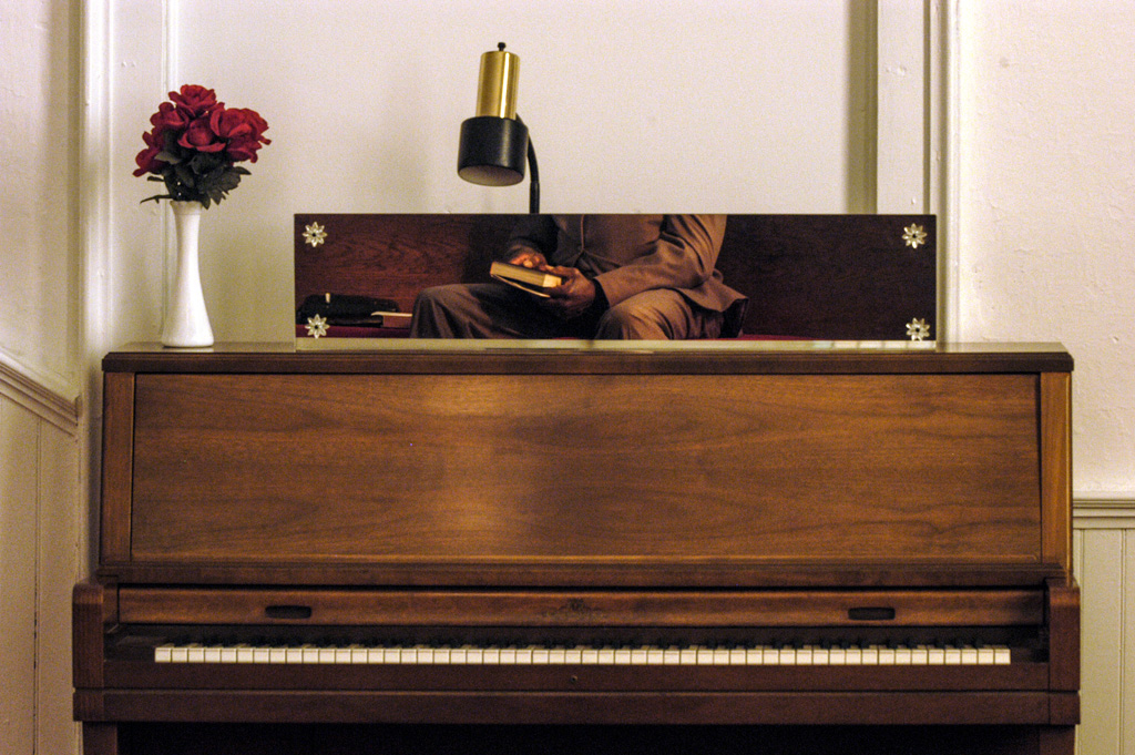 reflection of hands holding bible in mirror above piano